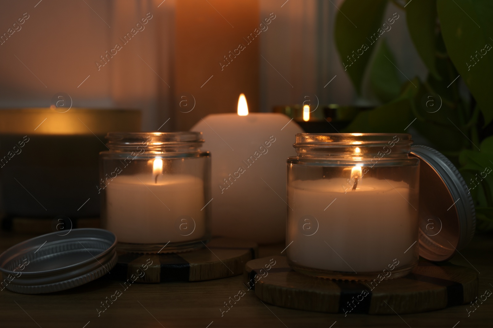 Photo of Burning candles on wooden table indoors, closeup