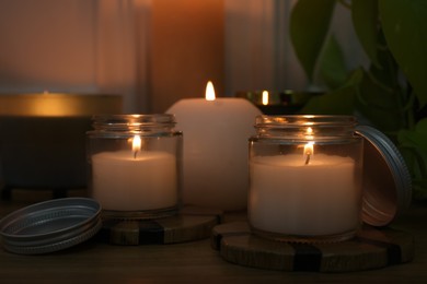 Burning candles on wooden table indoors, closeup