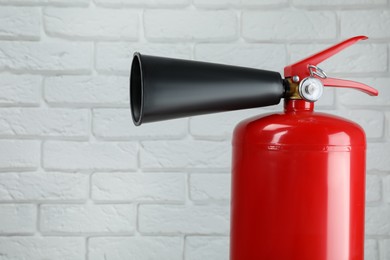 Fire extinguisher against white brick wall, closeup