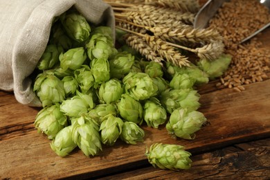 Photo of Fresh green hops, wheat grains and spikes on wooden table, closeup