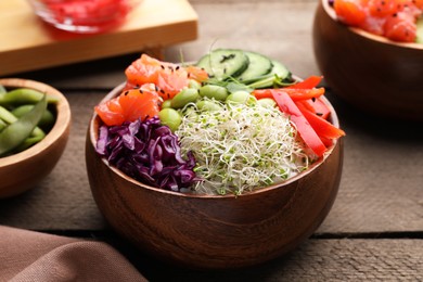 Delicious poke bowl with vegetables, fish and edamame beans on wooden table, closeup