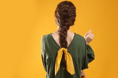 Photo of Woman with stylish bandana on yellow background, back view