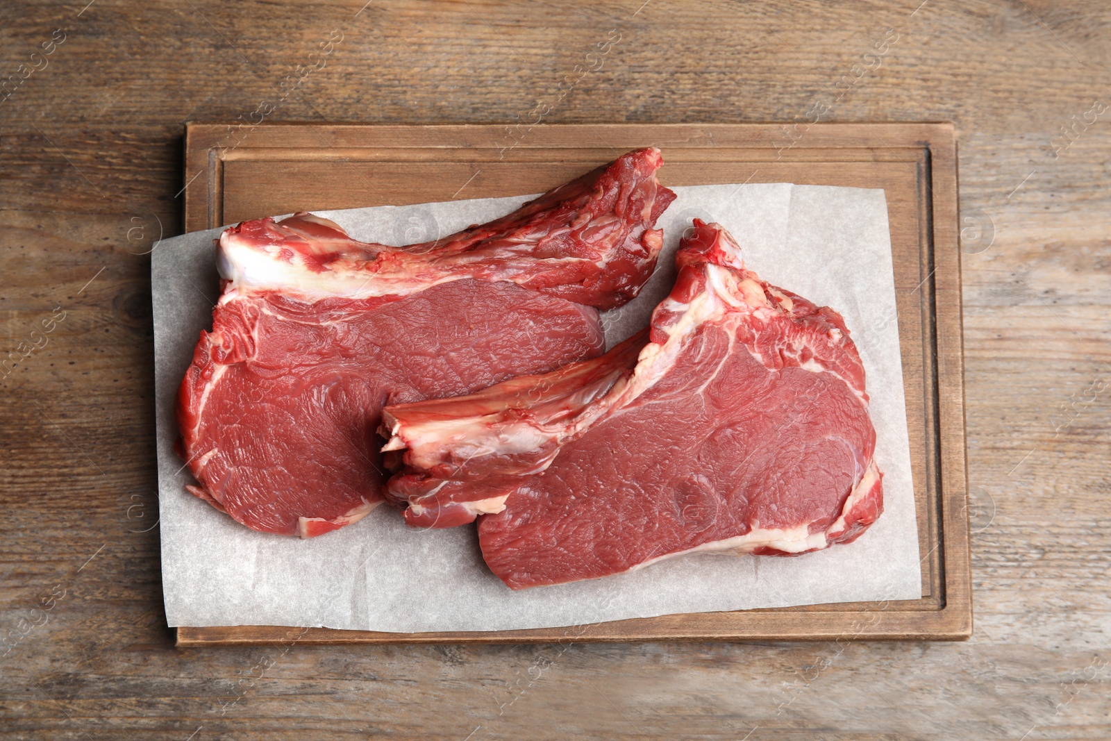 Photo of Fresh raw beef cut on wooden table, top view