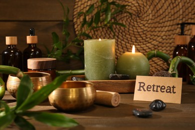 Card with word Retreat, singing bowls and burning candles on wooden table