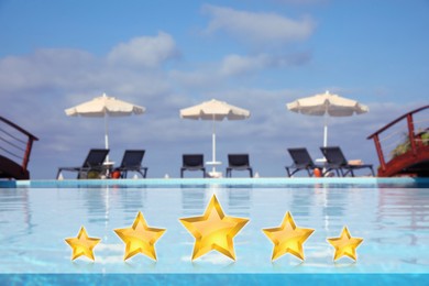 Image of Sunbeds near outdoor swimming pool at five star hotel