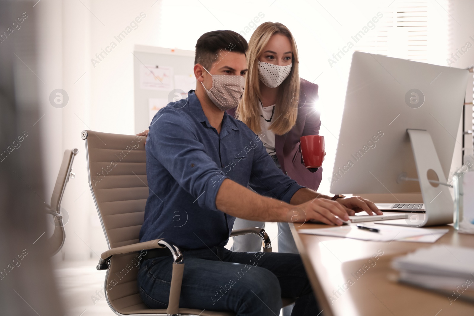 Photo of Coworkers with masks in office. Protective measure during COVID-19 pandemic