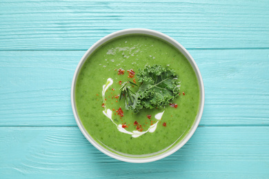Photo of Tasty kale soup on light blue wooden table, top view