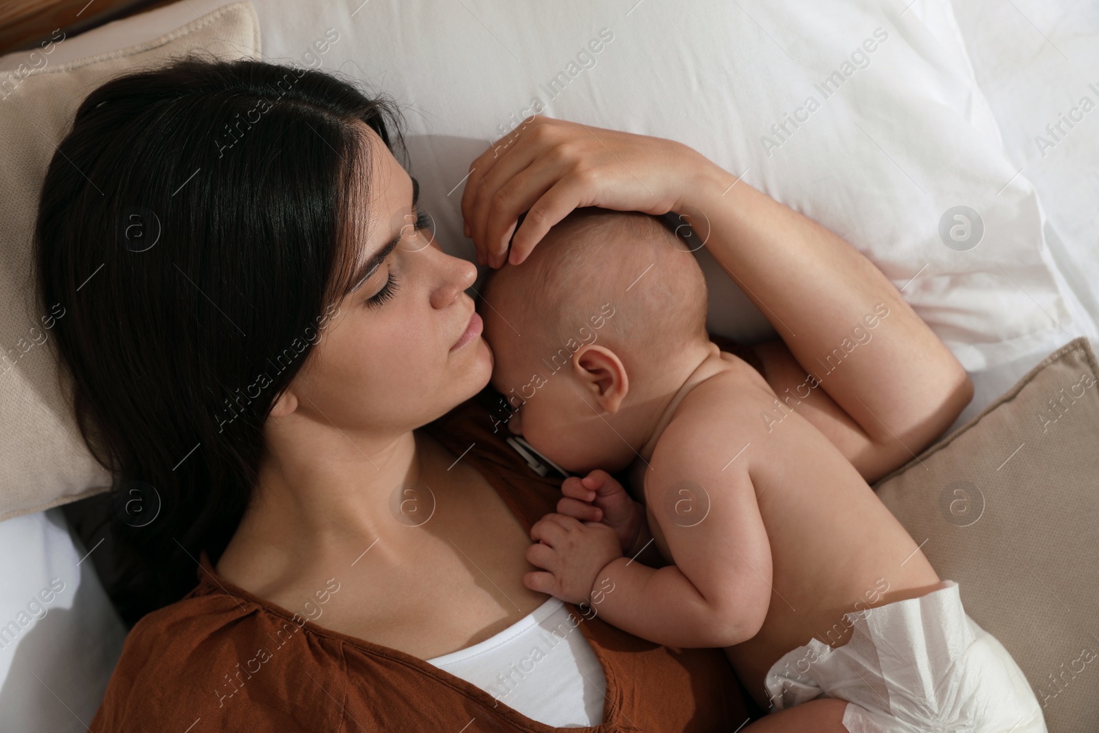 Photo of Mother with her cute baby sleeping on bed, top view