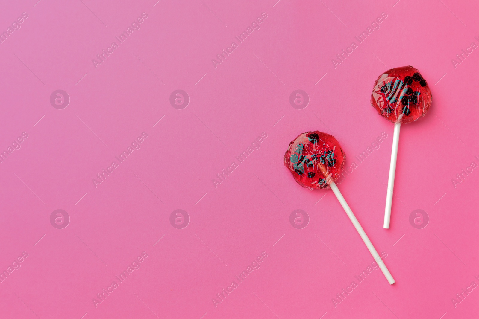 Photo of Sweet colorful lollipops with berries on pink background, flat lay. Space for text