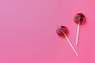 Photo of Sweet colorful lollipops with berries on pink background, flat lay. Space for text