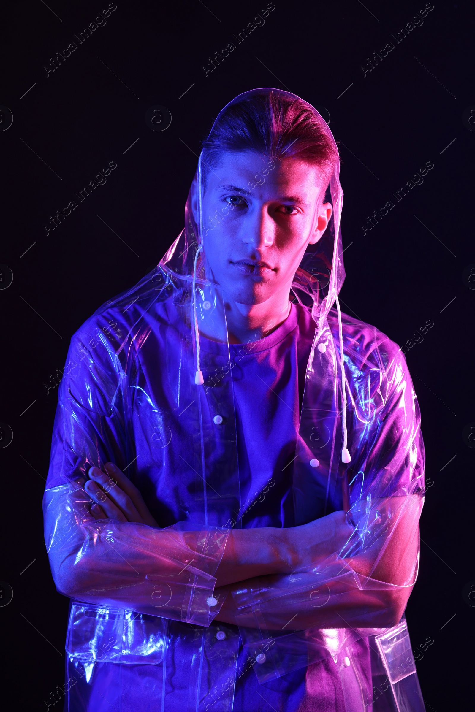 Photo of Young man wearing clear coat on dark background in neon lights