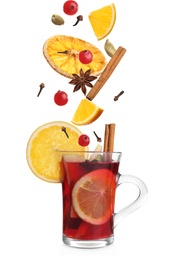 Image of Cut orange, cranberries and different spices falling into glass cup of mulled wine on white background 