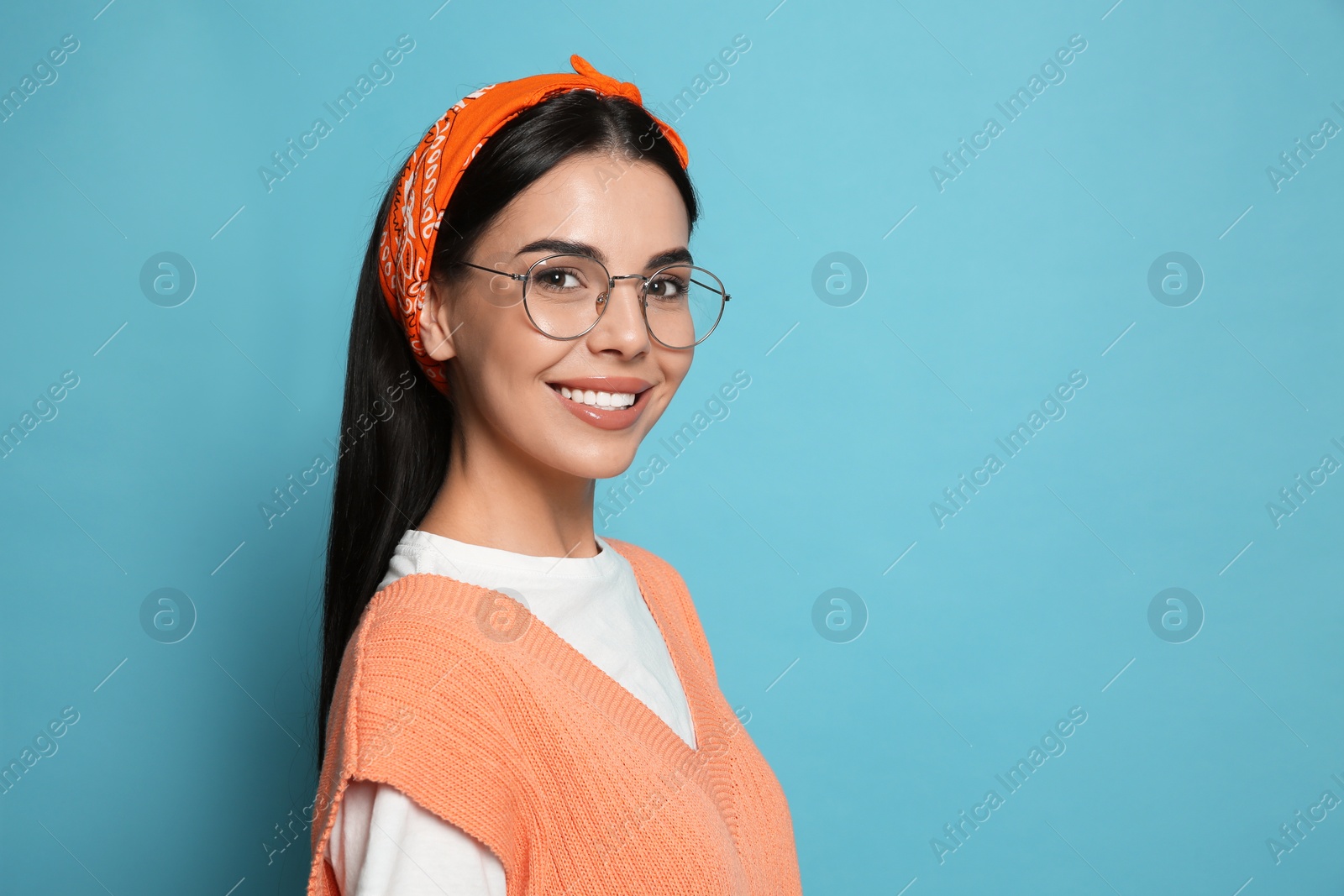 Photo of Young woman wearing stylish bandana on light blue background, space for text