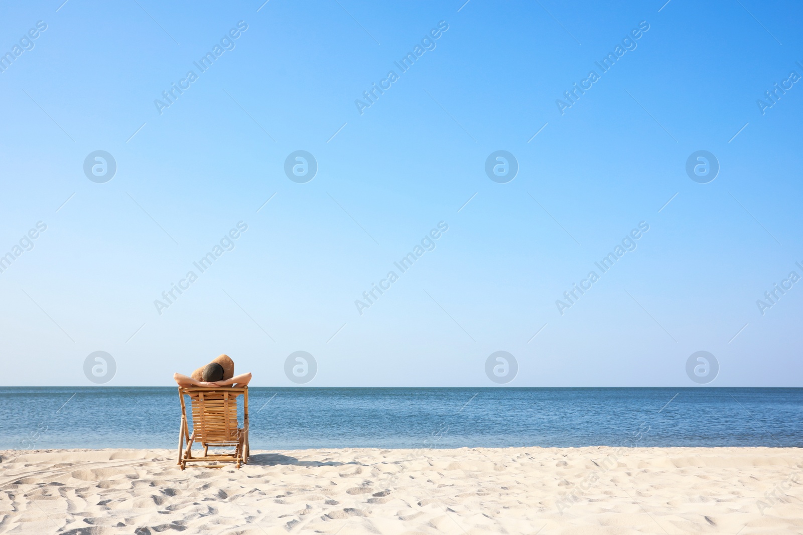 Photo of Young woman relaxing in deck chair on sandy beach