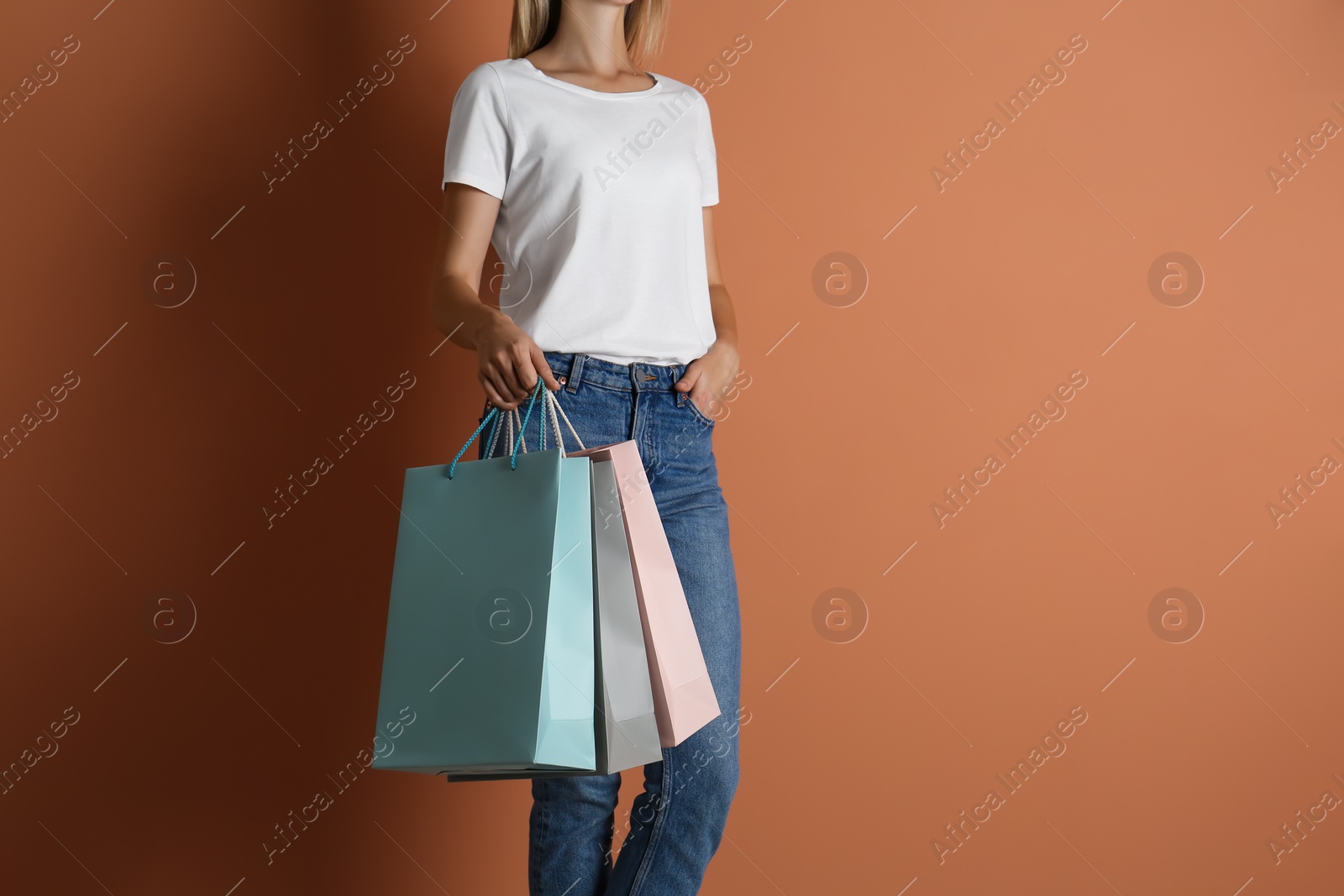 Photo of Woman with paper shopping bags on light brown background, closeup