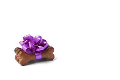 Photo of Bone shaped dog cookies with purple bow on white background, space for text