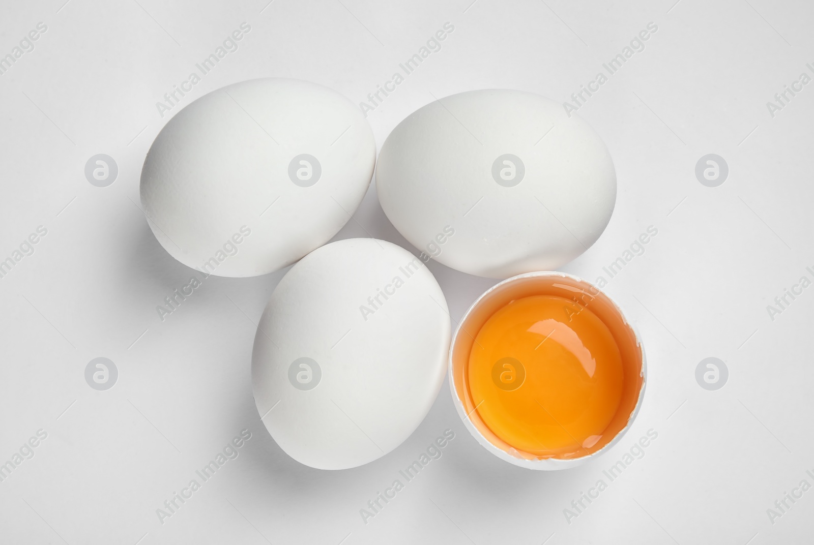 Photo of Cracked and whole chicken eggs on white background, top view