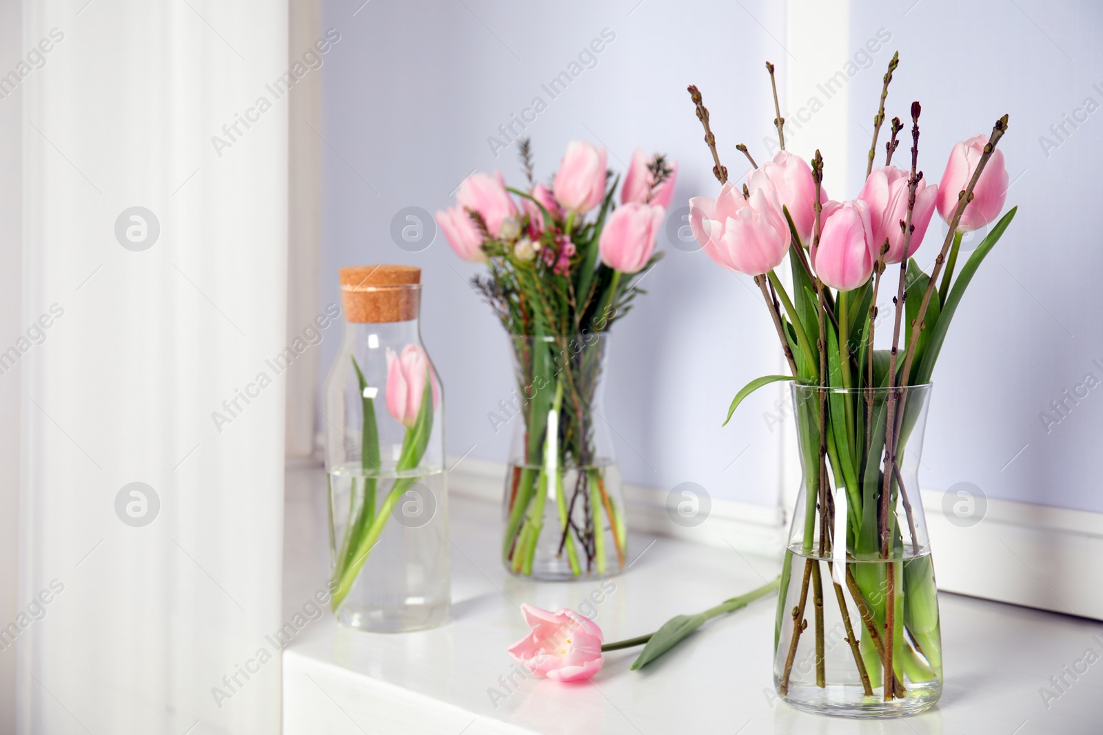 Photo of Beautiful bouquet with spring pink tulips on white window sill indoors