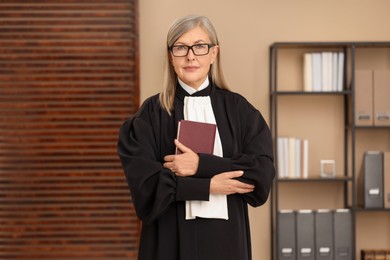 Portrait of judge in court dress with book indoors