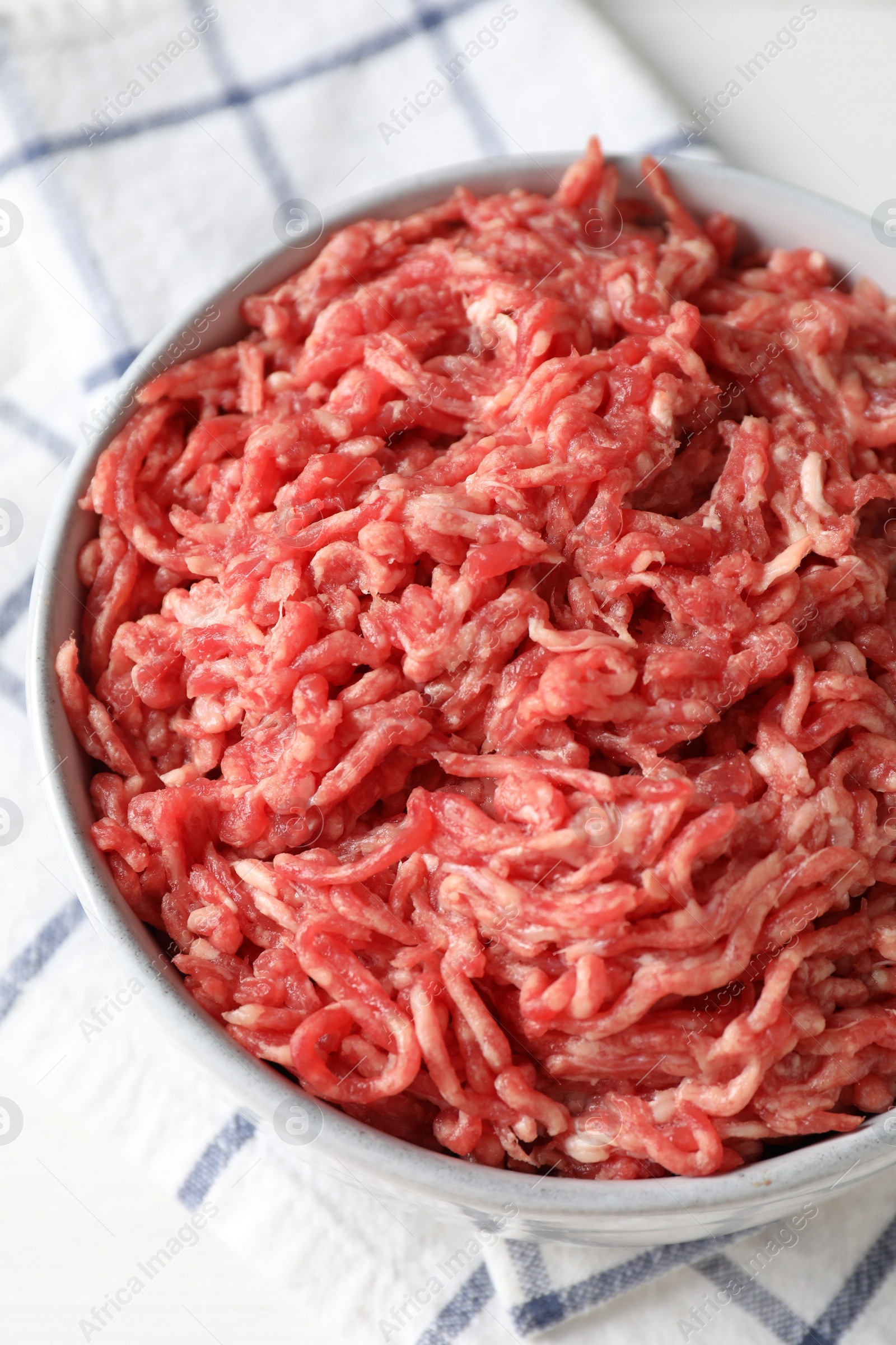 Photo of Raw ground meat in bowl on table, closeup