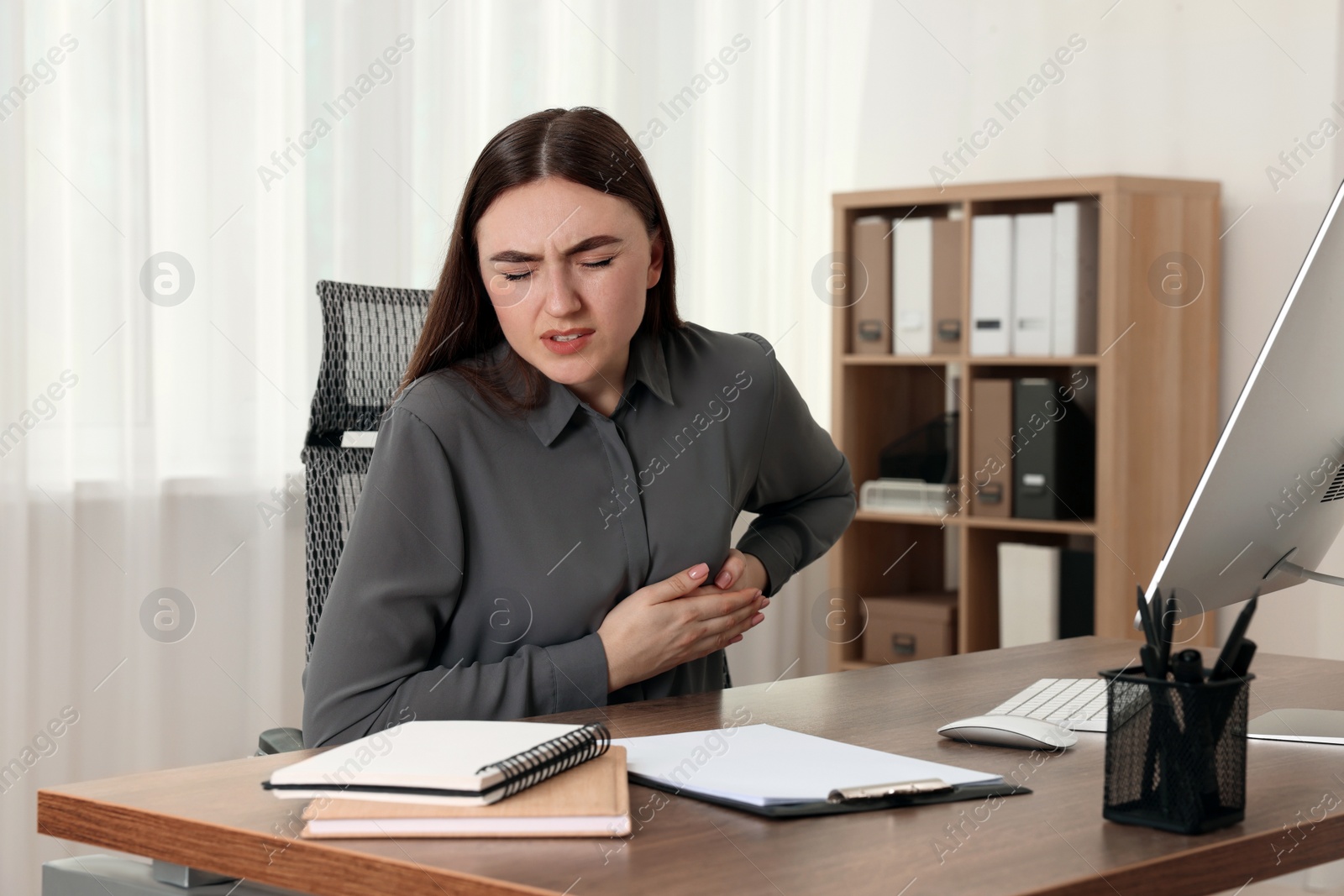 Photo of Woman having heart attack at table in office