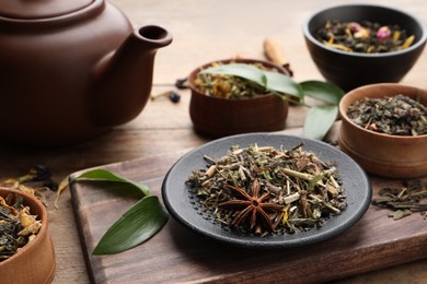 Photo of Different dry aromatic teas on wooden table