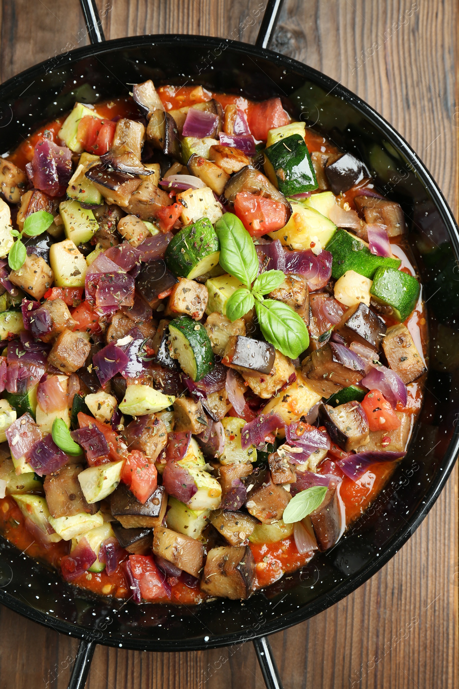 Photo of Delicious ratatouille in baking dish on wooden table, top view