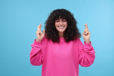 Photo of Woman crossing her fingers on light blue background