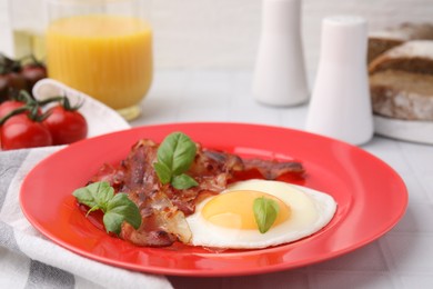 Fried egg, bacon and basil on white table