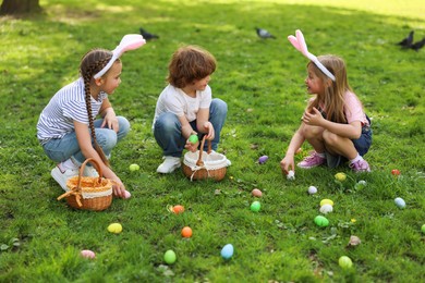 Photo of Easter celebration. Cute little children hunting eggs outdoors