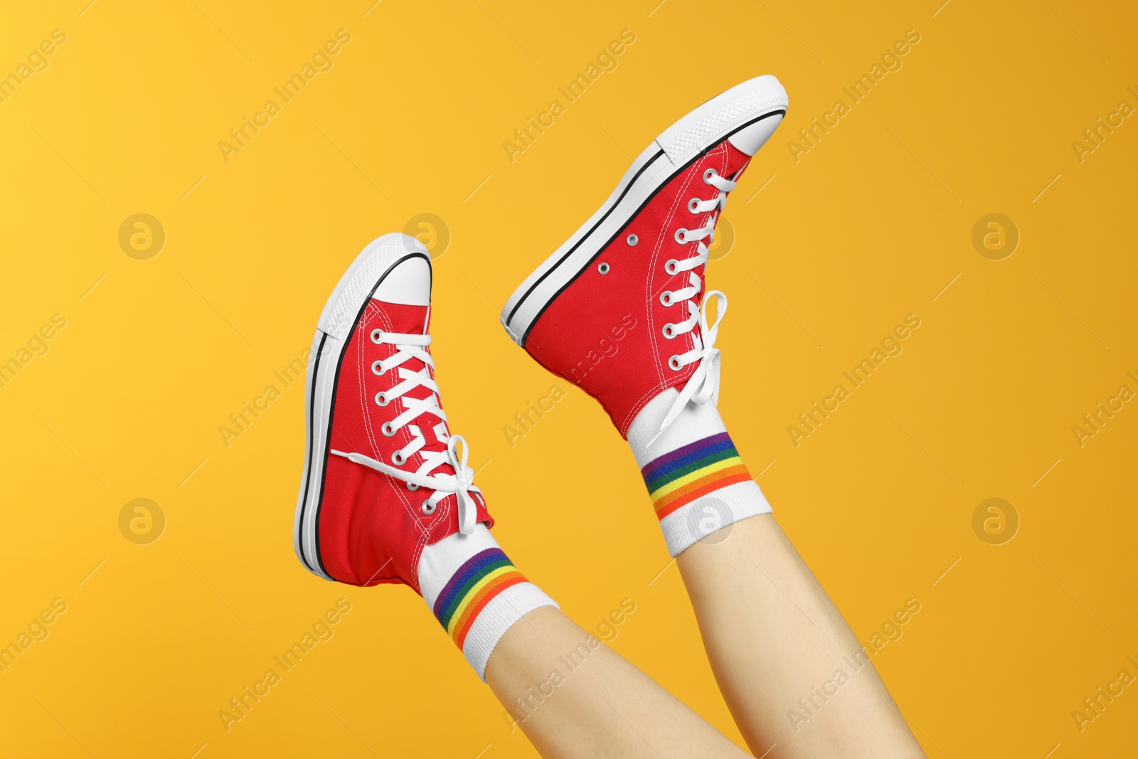 Photo of Woman in stylish gumshoes on yellow background, closeup