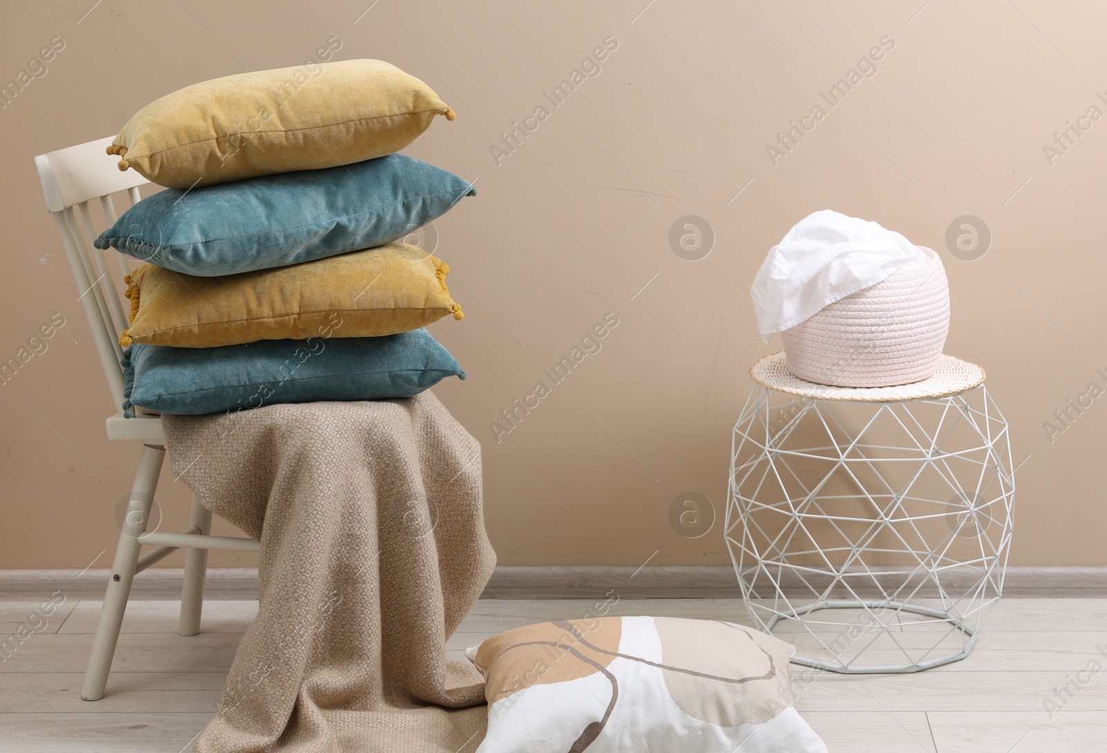 Photo of Soft pillows and warm blanket near beige wall indoors