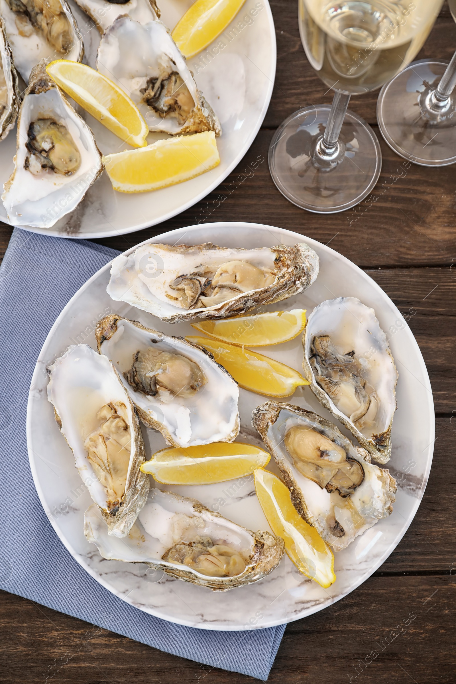 Photo of Fresh oysters with cut juicy lemon served on table, flat lay