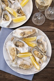 Fresh oysters with cut juicy lemon served on table, flat lay