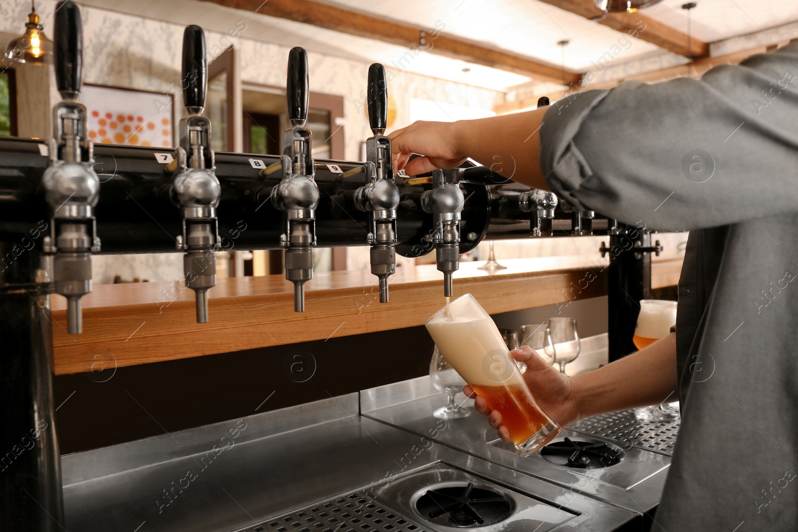 Photo of Bartender pouring fresh beer into glass in pub, closeup