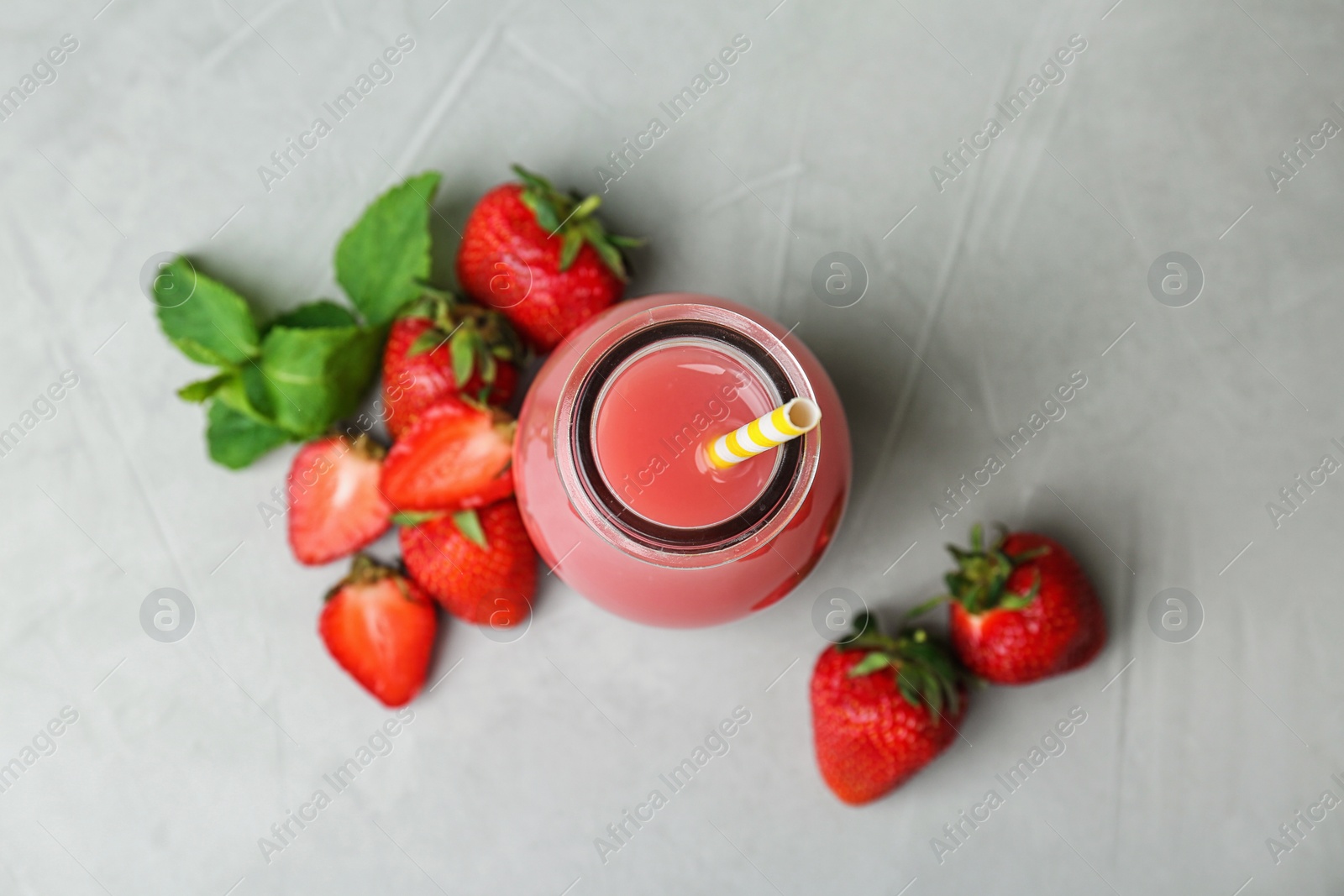 Photo of Flat lay composition with tasty strawberry juice in bottle on grey background