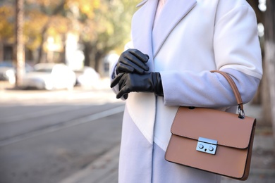Photo of Woman with leather gloves and stylish bag on city street, closeup