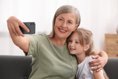 Happy grandmother taking selfie with her granddaughter at home