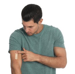Man putting sticking plaster onto arm on white background