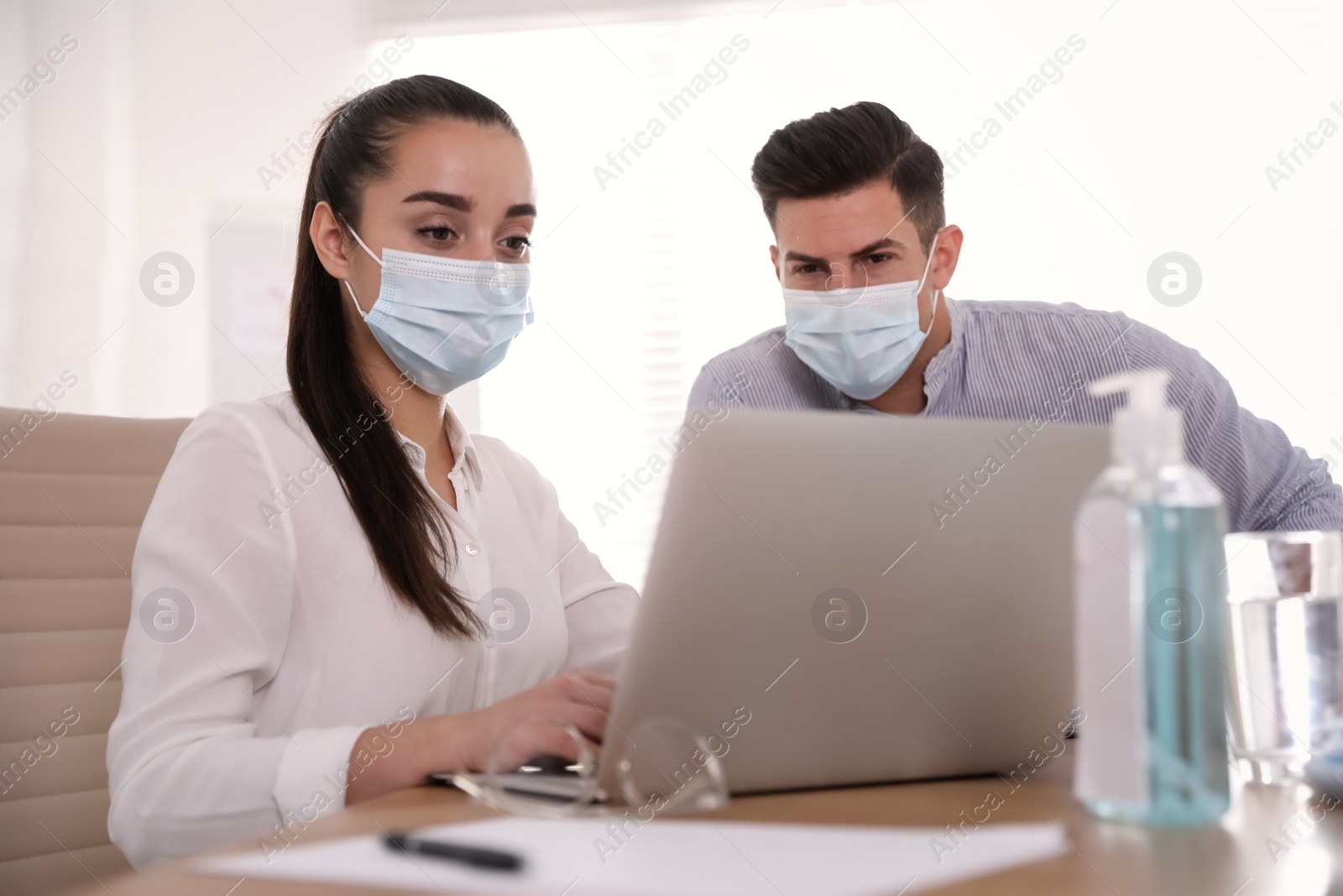 Photo of Coworkers with masks in office. Protective measure during COVID-19 pandemic