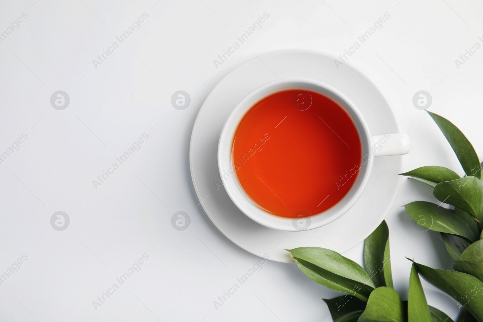 Photo of Cup of delicious tea with green leaves on light background, top view