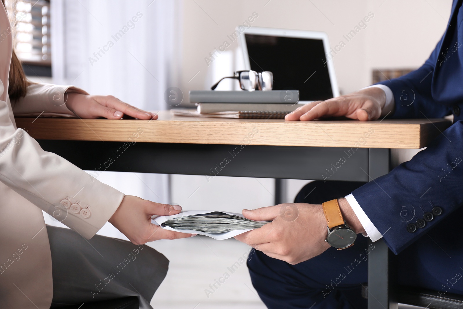 Photo of Woman giving bribe to man under table in office, closeup