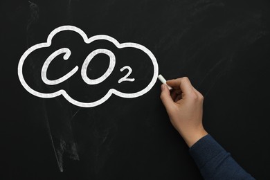Image of Reduce carbon emissions. Woman drawing cloud with chemical formula CO2 on blackboard, closeup