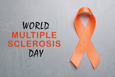 Multiple Sclerosis Awareness Day. Orange ribbon on light grey background, top view
