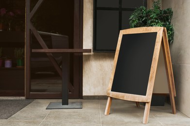 Photo of Blank wooden sandwich board near cafe outdoors. Mockup for design