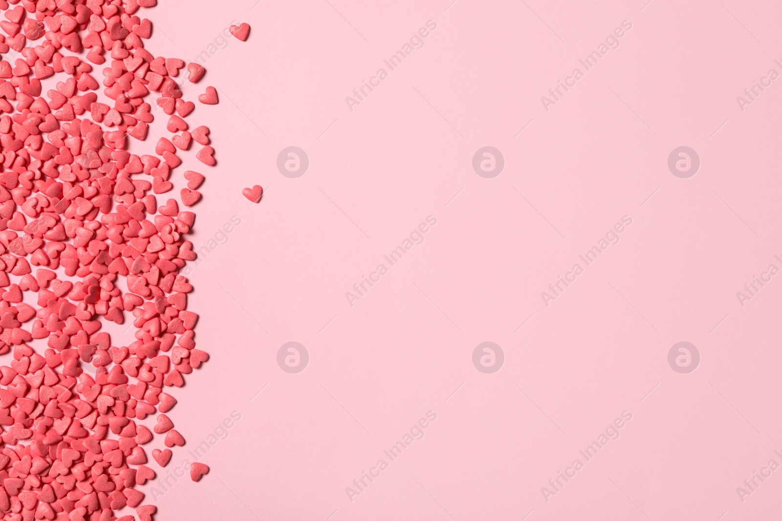 Photo of Heart shaped sprinkles on pink background, flat lay. Space for text