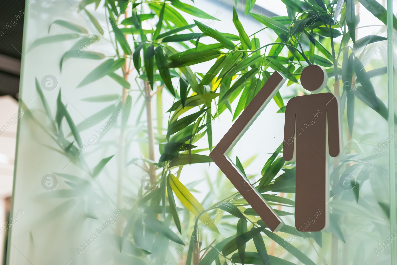 Image of Men's public toilet sign with arrow showing direction on glass wall