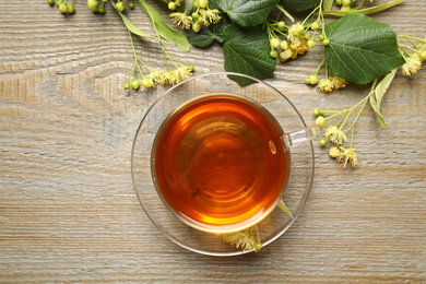 Cup of tea and linden blossom on wooden table, flat lay