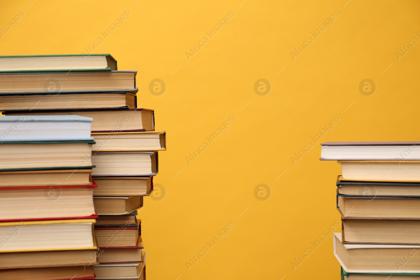 Photo of Many hardcover books on orange background, space for text. Library material