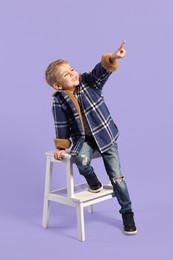 Fashion concept. Stylish boy posing on violet background